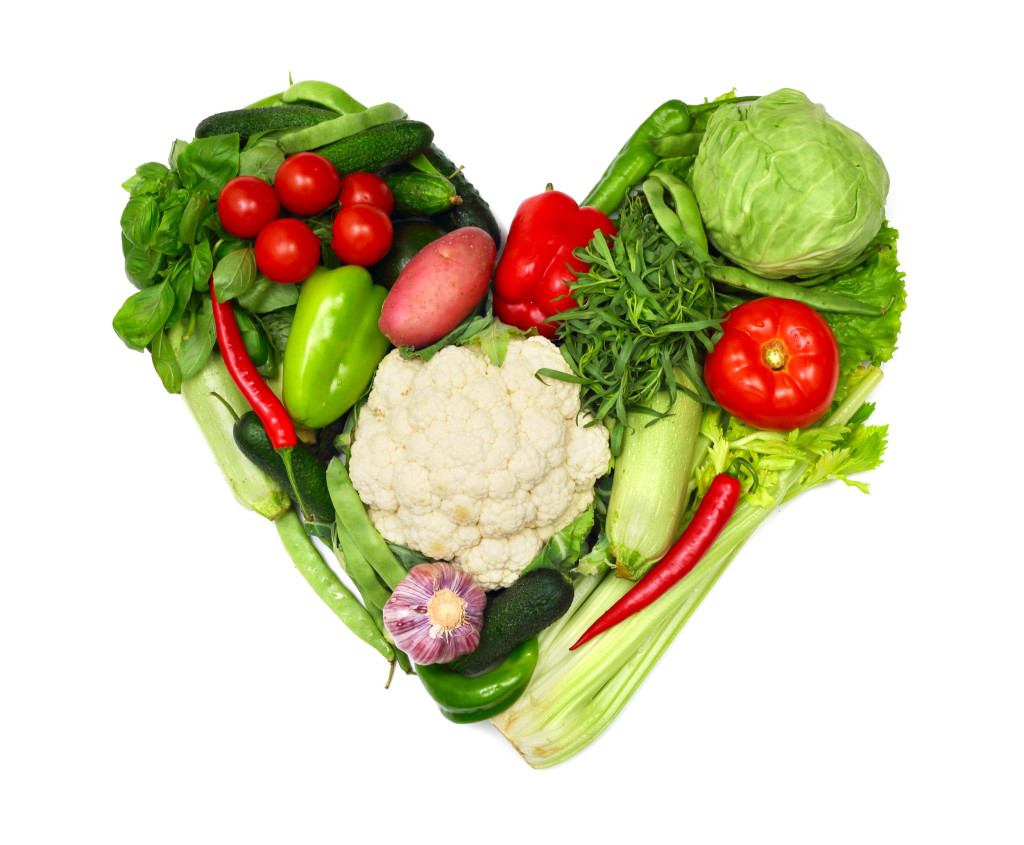Pile of vegetables shaped as heart isolated on white background